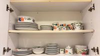 Two-shelf cabinet view showing dinnerware stacks and cups