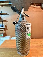 Full view of wire mesh seltzer bottle with dispenser top