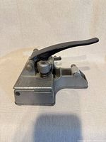 Side view of gray metal guillotine splicer showing lever