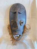 Full view of carved wooden mask with fiber beard