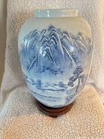 Front view of porcelain vase on stand showing blue mountain landscape