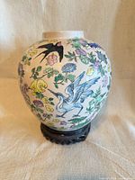 Front view of vase on stand showing bird and floral painting