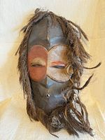 Full frontal view showing entire mask, paint colors and raffia hair