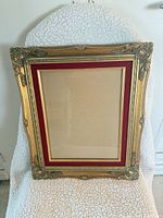 Full front view of ornate gold frame with red mat