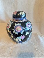 Front view of black porcelain ginger jar with floral pattern and lid