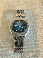 Front view of Seiko watch showing blue dial, day/date, bracelet