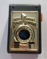 Front view closed showing gold logo plate and holographic lens