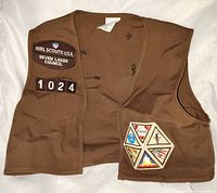 Full view of front of brown Girl Scouts USA vest showing council patch and troop number