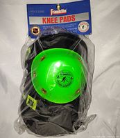 Front view of packaged knee pads showing green caps and branding