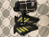 Side view of Adidas kids soccer cleats and strapped shin guards