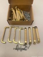 Box containing brass-colored pulls and screws