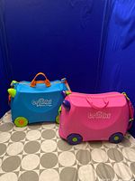 Front view of blue and pink Trunki suitcases closed