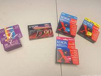 Front view of sealed Kodak film, TDK cassette, and three Xerox ink cartridges showing models and colours