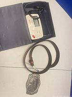 All three items laid out: monitor in box, leather belt, separate metal buckle