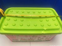 Top view of green studded lid with measuring tape showing length