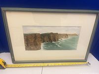 Front view of framed watercolor painting with measuring tape for scale