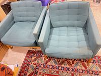 Front top view of both teal armchairs showing tufted cushions, wood bases