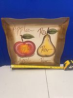 Front view of square ceramic platter with apple and pear artwork, tape measure showing ~15 in width