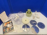 overall view of all accessories laid out including bowls, discs, beaters, juicer and manuals