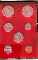 Open case showing seven specimen coins in red flocked insert