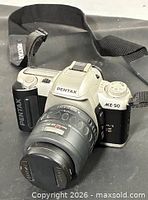 Front three-quarter view of camera with lens, cap, and strap