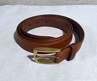 Full view of coiled brown leather belt showing buckle and strap