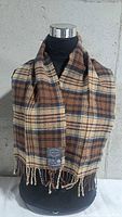Full view of scarf draped on mannequin showing plaid pattern and fringe