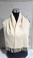 Full view of cream cashmere scarf with fringes displayed on mannequin