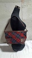 Front view of tartan shoulder bag on mannequin showing pattern, leather trim and orb logo