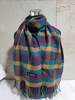 Full view of plaid cashmere scarf draped on mannequin with visible fringe and brand label