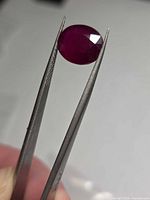 Ruby held in tweezers showing table and pavilion facets