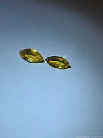 Two marquise-cut yellow sapphires side by side on white surface