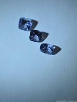 Three cushion-cut tanzanite stones on neutral background