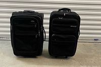 Front view of both black Samsonite suitcases standing closed