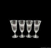 Front view of four matching etched champagne glasses