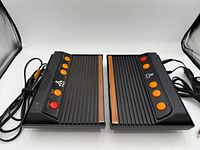 Two Atari Flashback consoles side by side displaying tops and attached cables