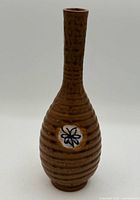 Front view of long neck brown ribbed vase with blue floral medallion