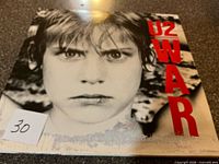 Angled view of front album cover showing child image and red U2 War text with lot number