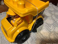 Front angle of CAT plastic dump truck with driver figure visible
