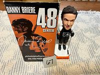 Bobblehead standing beside original box, lot identifier visible