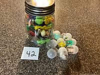 Full view of jar packed with small toys and loose capsules beside it