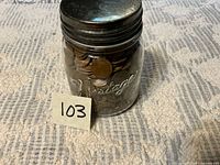 Front view of glass jar filled with wheat pennies, metal lid visible