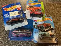 Four unopened Hot Wheels packages laid out showing car names and colors