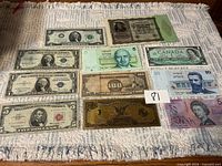Group shot showing all eleven banknotes laid out on cloth surface