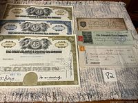 Overview of three A&P stock certificates and three vintage checks on table