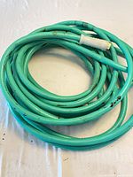 Coiled teal vinyl garden hose showing entire length and fittings