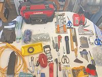 Overview of all items on table including Husky bag, Milwaukee chargers, hand tools