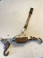 Full view of steel come-along winch showing handle, hooks, pulley, and cable