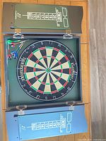 Cabinet open showing dartboard, darts, and both scoreboard doors