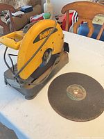 Overall view of DeWalt chop saw with loose wheel beside it